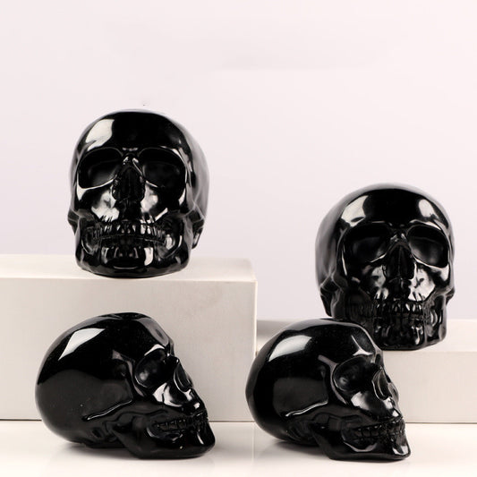 Vier handgefertigte Obsidian Kristallschädel auf weißen Sockeln, edles Deko-Stück aus echtem Obsidianstein.