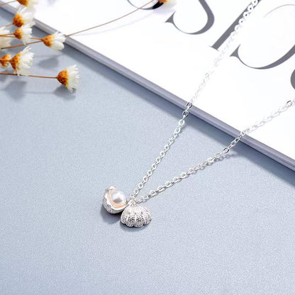 Elegante Halskette aus Sterlingsilber mit Muschelperle und floralen Anhänger auf hellem Hintergrund.