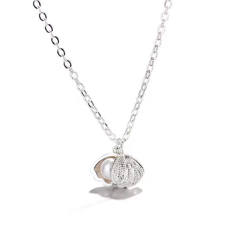 Elegante Halskette aus Sterlingsilber mit Muschelperle und floralen Anhänger auf hellem Hintergrund.