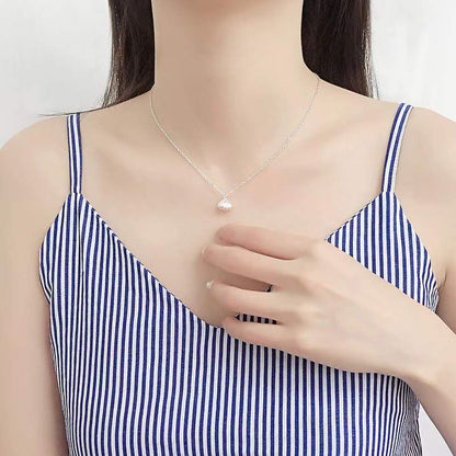 Elegante Halskette aus Sterlingsilber mit Muschelperle, getragen von einer Frau in einem gestreiften Top.